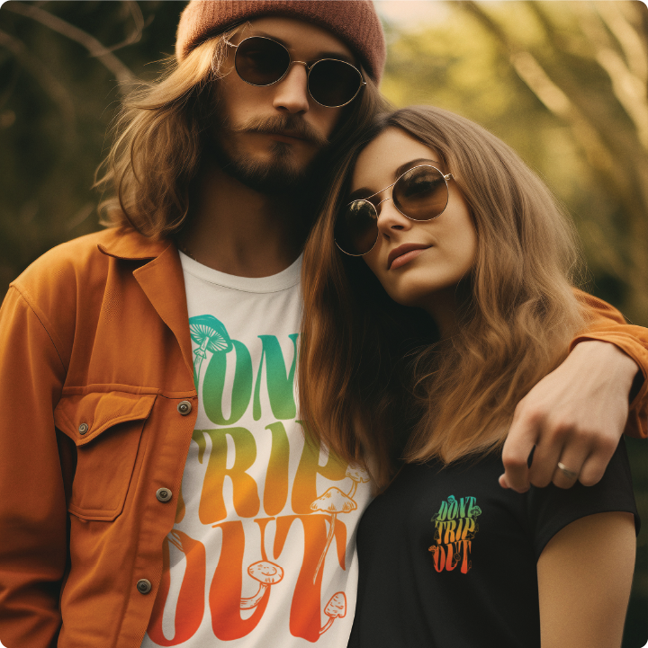 A couple wearing sunglasses and retro-style shirts with colorful designs stand closely together in a sunlit outdoor setting.