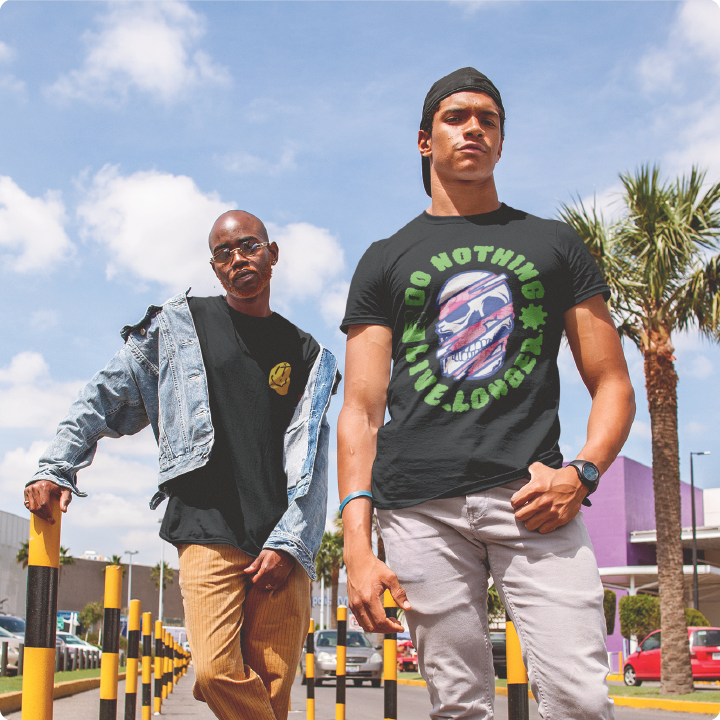 Two men pose confidently on a street, one wearing a denim jacket and the other a black T-shirt. Palm tree and building in the background.